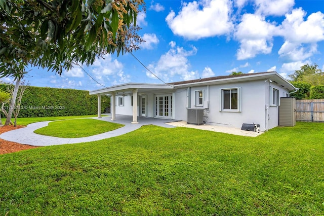 back of house featuring central air condition unit, a patio area, a yard, and stucco siding