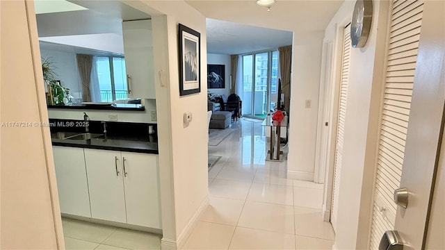 hallway featuring light tile patterned flooring, a sink, and baseboards