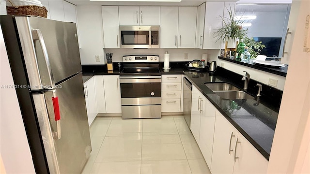 kitchen featuring light tile patterned floors, stainless steel appliances, a sink, and white cabinetry