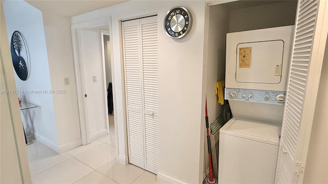 laundry room featuring light tile patterned floors, baseboards, laundry area, and stacked washer and clothes dryer