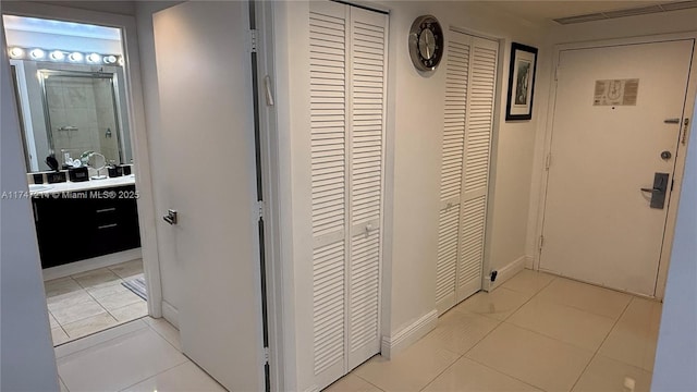 hall featuring light tile patterned flooring and baseboards