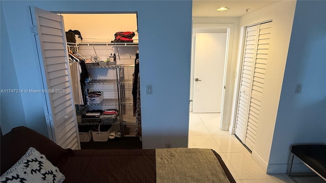 tiled bedroom with a walk in closet and a closet