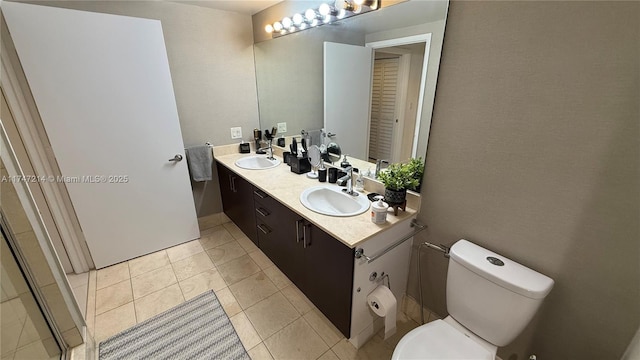 bathroom with double vanity, a sink, toilet, and tile patterned floors