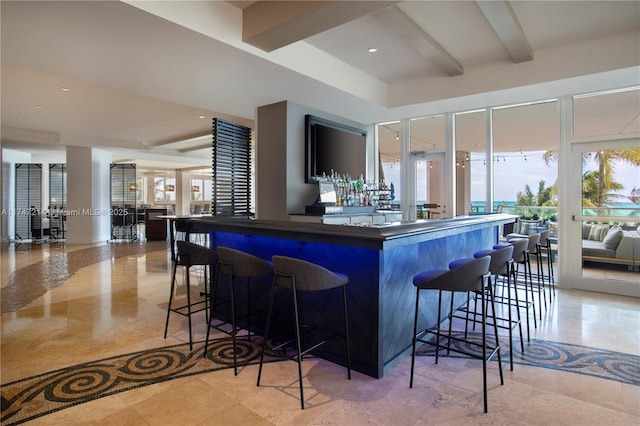 kitchen with dark countertops, a large island, a kitchen breakfast bar, and beamed ceiling