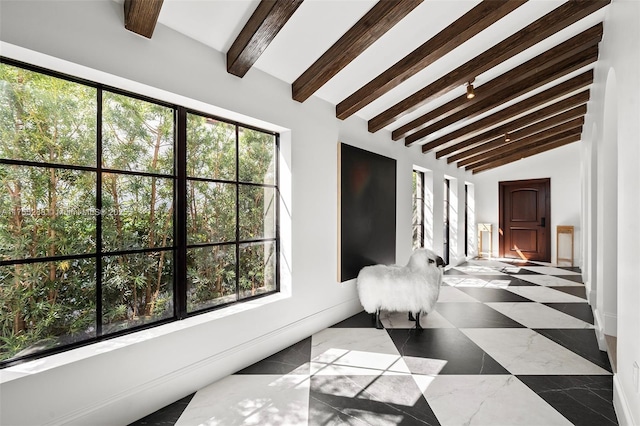 interior space with a wealth of natural light and vaulted ceiling with beams