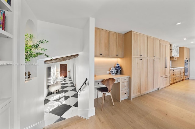 kitchen featuring light wood finished floors, recessed lighting, light countertops, light brown cabinetry, and double oven