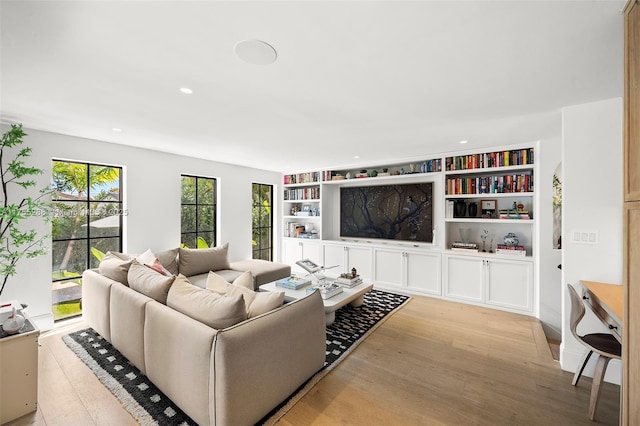 living area with built in shelves, wood finished floors, and recessed lighting