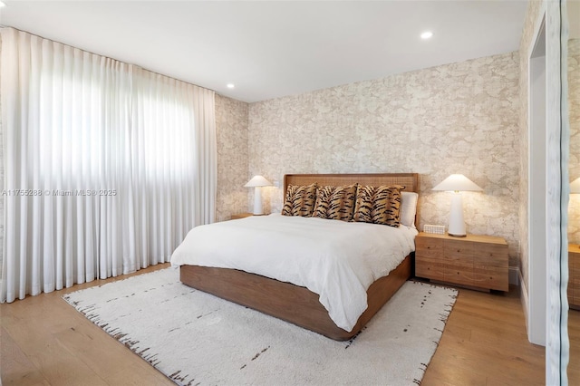 bedroom with wallpapered walls, wood finished floors, and recessed lighting