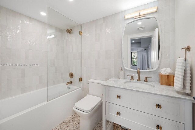 full bath featuring visible vents, bathing tub / shower combination, toilet, vanity, and tile walls