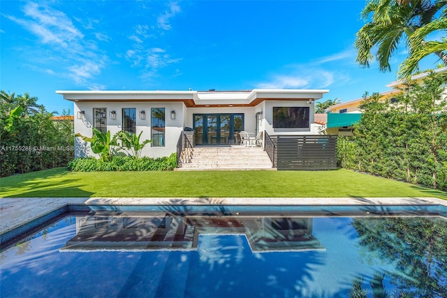 back of property with french doors, a lawn, and stucco siding