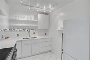 kitchen featuring stove, white cabinets, a sink, and light countertops