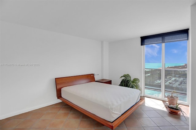 bedroom with light tile patterned floors, access to outside, expansive windows, and baseboards