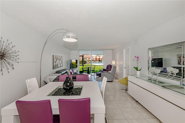 dining area with a wall of windows, visible vents, light tile patterned flooring, and a textured ceiling