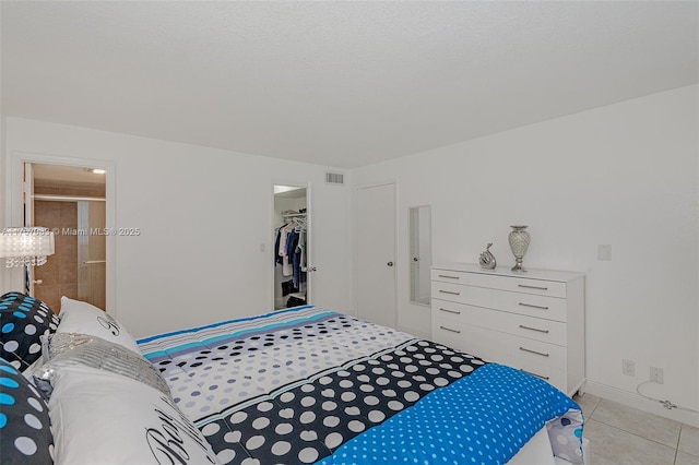 bedroom with light tile patterned floors, a spacious closet, visible vents, and a closet