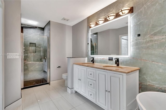 full bathroom with double vanity, a stall shower, tile walls, and a sink