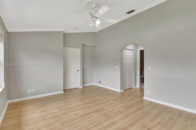 unfurnished room featuring arched walkways, visible vents, light wood-style floors, ornamental molding, and ceiling fan