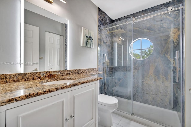 full bathroom with toilet, tile patterned flooring, a marble finish shower, and vanity