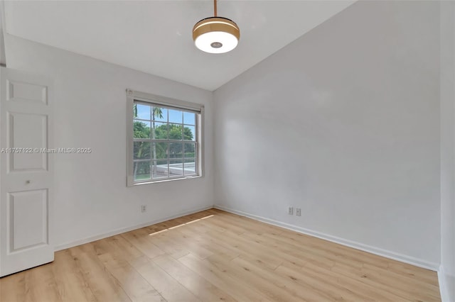 unfurnished room with baseboards, vaulted ceiling, and light wood finished floors