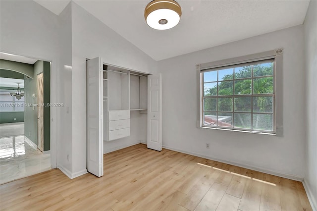 unfurnished bedroom with lofted ceiling, baseboards, arched walkways, and wood finished floors