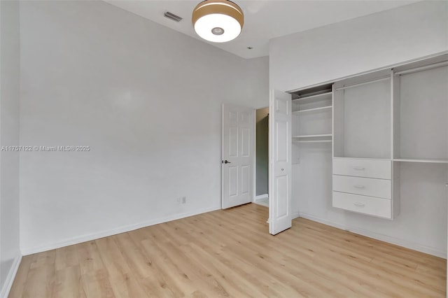 unfurnished bedroom featuring light wood-style floors, baseboards, visible vents, and a closet