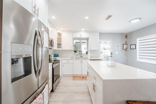 kitchen with light wood-style flooring, visible vents, white cabinetry, appliances with stainless steel finishes, and a center island