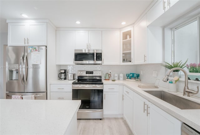 kitchen with stainless steel appliances, white cabinetry, a sink, and decorative backsplash