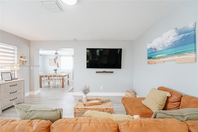 living room featuring light wood-type flooring, visible vents, and baseboards