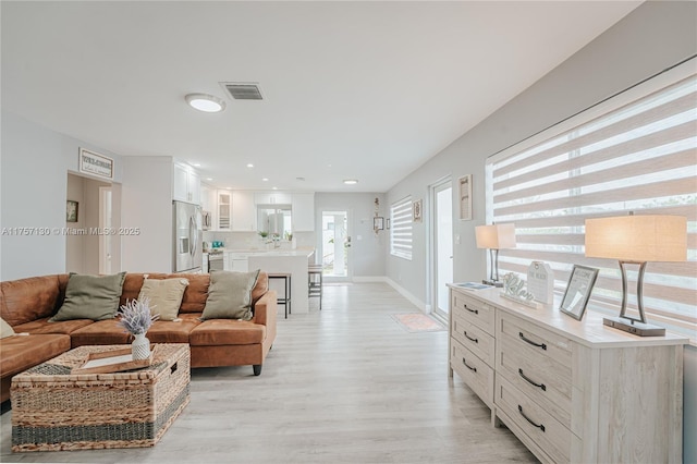 living room with baseboards, recessed lighting, visible vents, and light wood-style floors