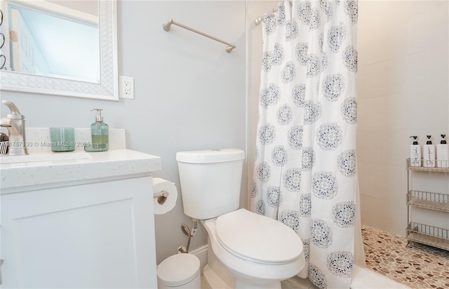 bathroom featuring toilet, a tile shower, and vanity