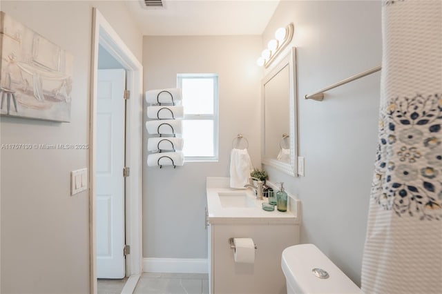 bathroom with toilet, vanity, and baseboards