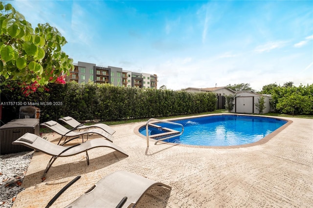 view of pool featuring a storage shed, a patio area, an outbuilding, and a fenced in pool