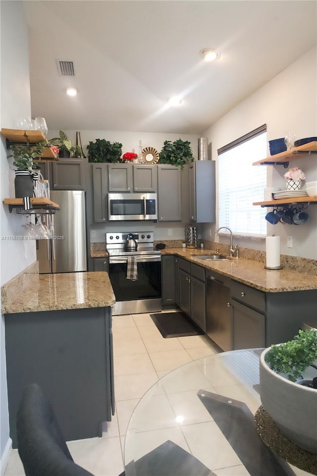 kitchen featuring a sink, stainless steel appliances, light stone counters, and open shelves