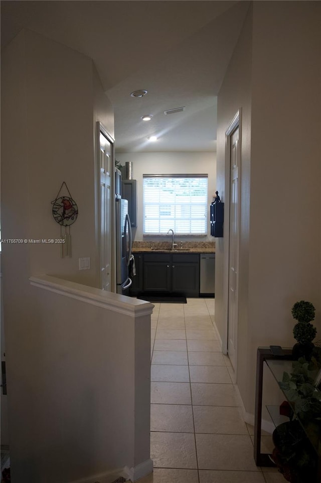 corridor featuring light tile patterned floors, a sink, and visible vents