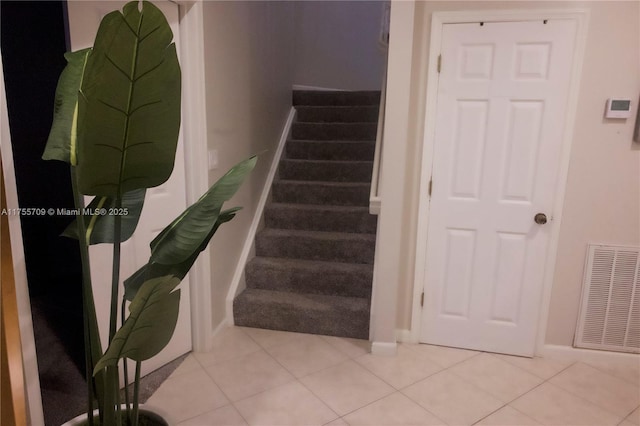 staircase with baseboards, visible vents, and tile patterned floors