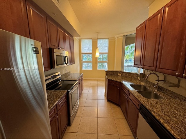 kitchen featuring light tile patterned floors, stainless steel appliances, a sink, dark stone countertops, and baseboards