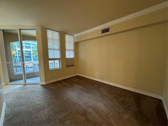 empty room with visible vents, dark carpet, baseboards, and ornamental molding