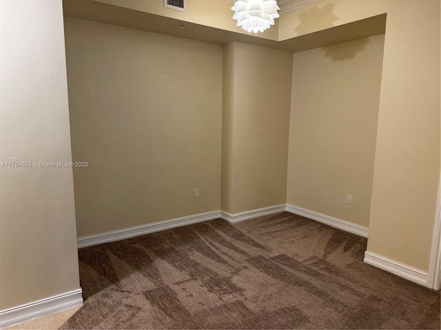 carpeted spare room with visible vents, baseboards, and an inviting chandelier