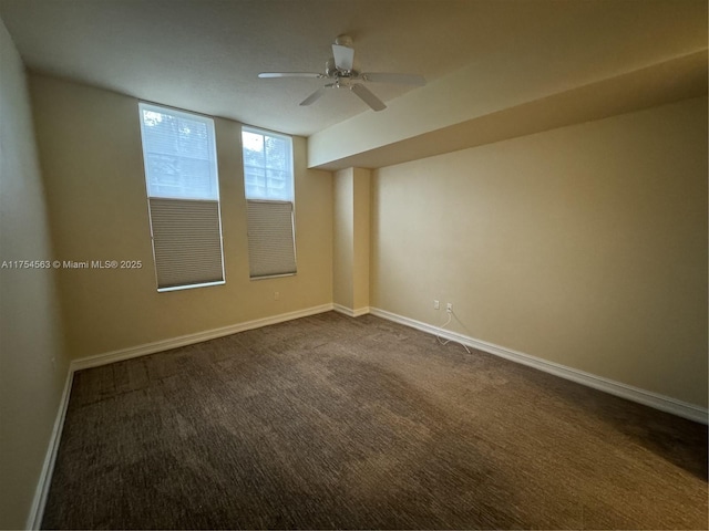 spare room with ceiling fan, baseboards, and dark colored carpet