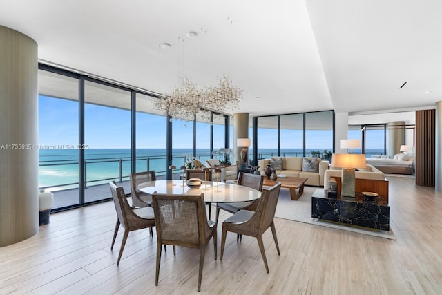 dining room featuring a water view, light wood-style flooring, and floor to ceiling windows