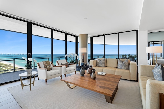 living area with a wealth of natural light, expansive windows, a water view, and wood finished floors