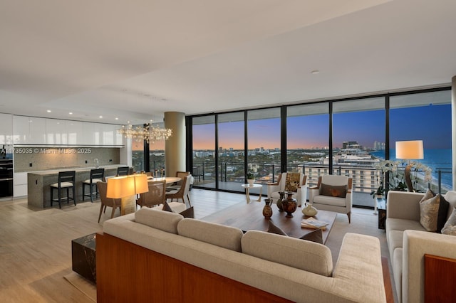 living room with light wood finished floors, expansive windows, and an inviting chandelier