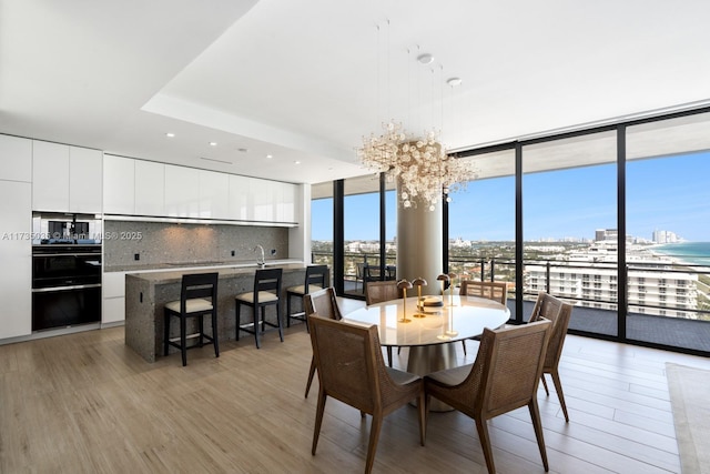 dining space with light wood-style floors, expansive windows, a city view, and recessed lighting