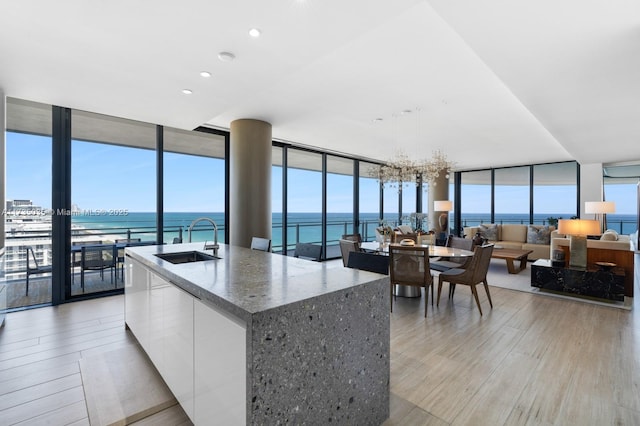 kitchen featuring a wall of windows, modern cabinets, a sink, and white cabinets