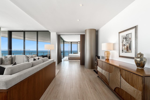 living room featuring a wall of windows, a water view, and light wood-style floors