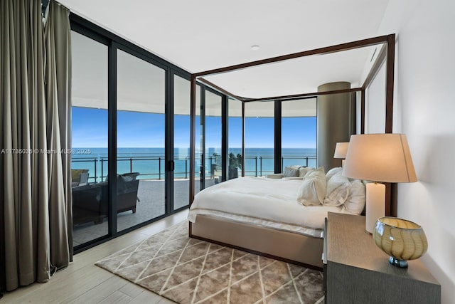 bedroom with expansive windows, access to outside, multiple windows, and a water view