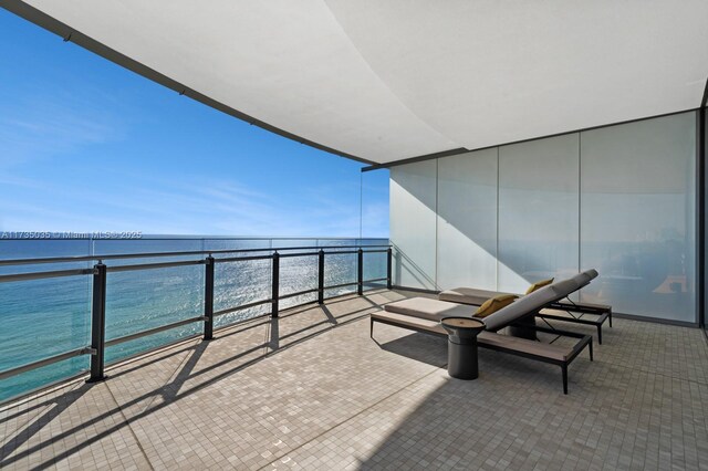 balcony with a water view and a view of the beach