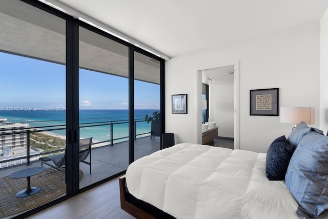 bedroom featuring a wall of windows, multiple windows, a water view, and wood finished floors