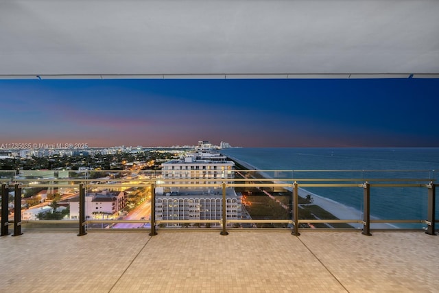 patio terrace at dusk featuring a view of city and a water view