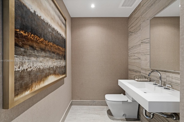 bathroom with marble finish floor, visible vents, toilet, a sink, and baseboards