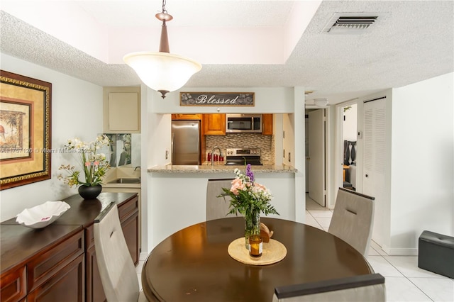 dining room featuring light tile patterned floors, a textured ceiling, and visible vents